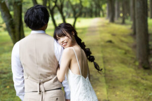 富山の頼成の森で森林の中寄り添うドレス姿の新郎新婦の前撮りフォトウェディング