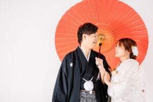 富山のフォトスタジオで番傘(和傘)の中で見つめ合い笑顔の和装フォトウェディングの新郎新婦