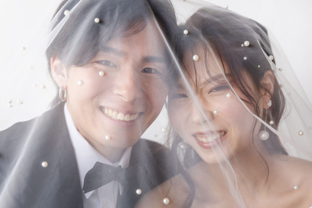 パール付きのベールを被った新郎新婦