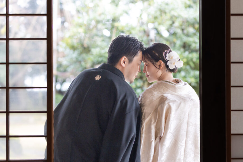 縁側で額を合わす和装新郎新婦
