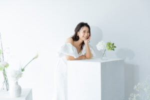 富山のフォトスタジオで白のシンプルな装飾の中微笑む洋装新婦のソロフォトウェディング