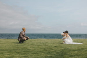 富山の海老江海浜公園でしゃがむ洋装新郎新婦と子供のロケーションフォトウェディング