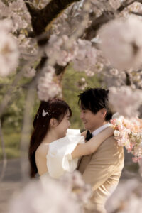 富山県の桜のロケーションで撮影されたフォトウェディングの洋装の花嫁。満開の桜の下で微笑む美しい花嫁の写真