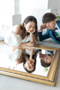 富山のフォトウェディングでシンプルな白を基調としたスタジオで白と緑の生花に囲まれて微笑む洋装新郎新婦