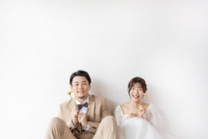 富山のスタジオで生花を持って笑顔を見せる洋装新郎新婦のフォトウェディング