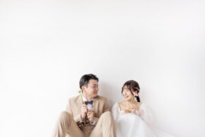 富山のスタジオで生花を持って笑顔を見せる洋装新郎新婦のフォトウェディング