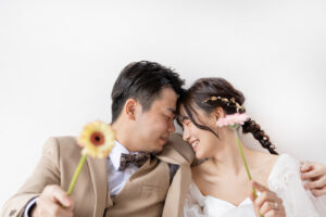 富山のスタジオで生花を持って額を寄せ合う洋装新郎新婦のフォトウェディング