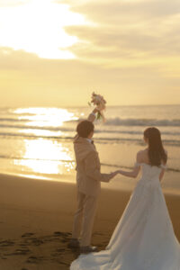 夕日に向かってブーケを上に高く上げている新郎新婦の富山フォトウェディング