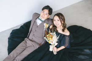 富山のコアラで新郎新婦がブラックドレスをきて座ってブーケを持っている富山フォトウェディング