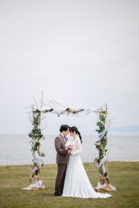 富山のコアラで海老江海岸で新郎新婦がおでこを寄せ合ってブーケを持っている富山フォトウェディング
