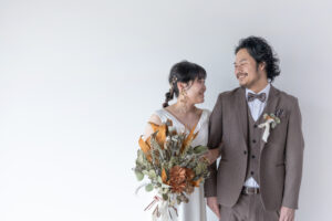 富山のコアラで洋装スタジオフォトウェディングを行なった新郎新婦がブーケを持って微笑み合っている様子