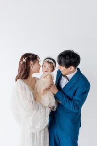 富山のコアラで洋装スタジオフォトウェディングを行なっている新郎新婦と赤ちゃんを見ているフォトウェディング