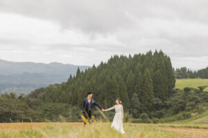 富山のコアラで草原の中で手を繋いで見つめ合っているフォトウェディング