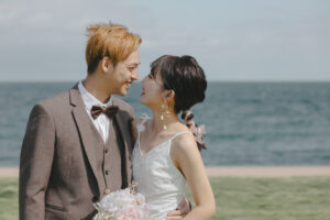 富山のコアラで洋装ロケーションフォトウェディングを海で行なった新郎新婦が笑い合っている