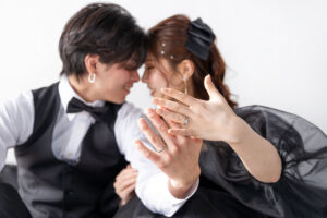 富山のコアラのスタジオでブラックドレスを着て撮影している新郎新婦が手元を見せておでこを寄せ合っている様子